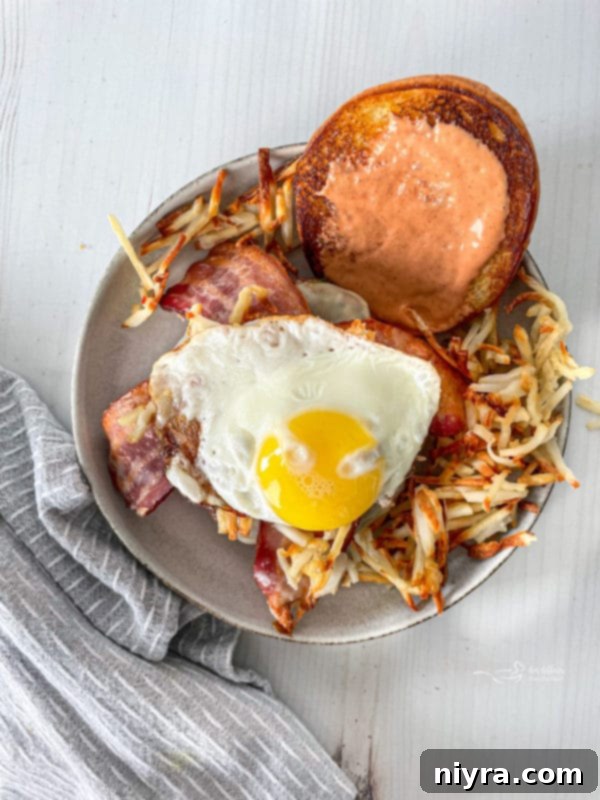 A fully assembled Hangover Burger with hash browns and bacon visible