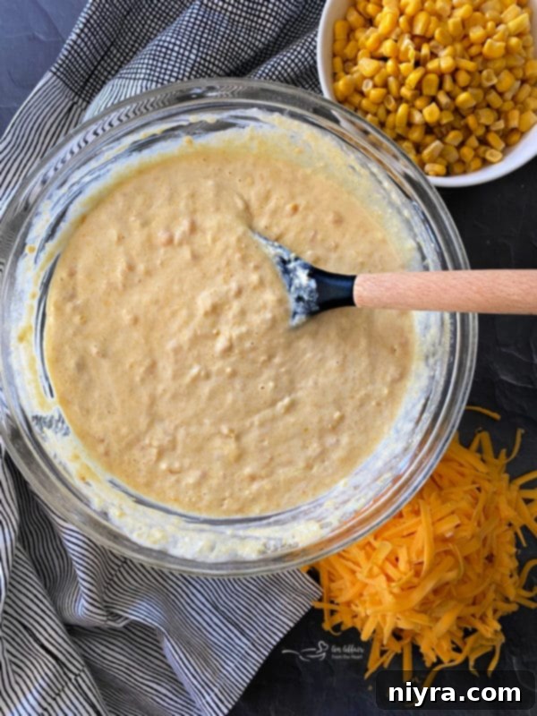 Golden Corn Bake 8 Close-up view of corn mixture in a large mixing bowl with a spoon, perfectly combined.