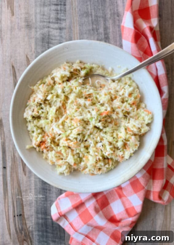 Creamy Copycat KFC Coleslaw in a white bowl with a serving spoon