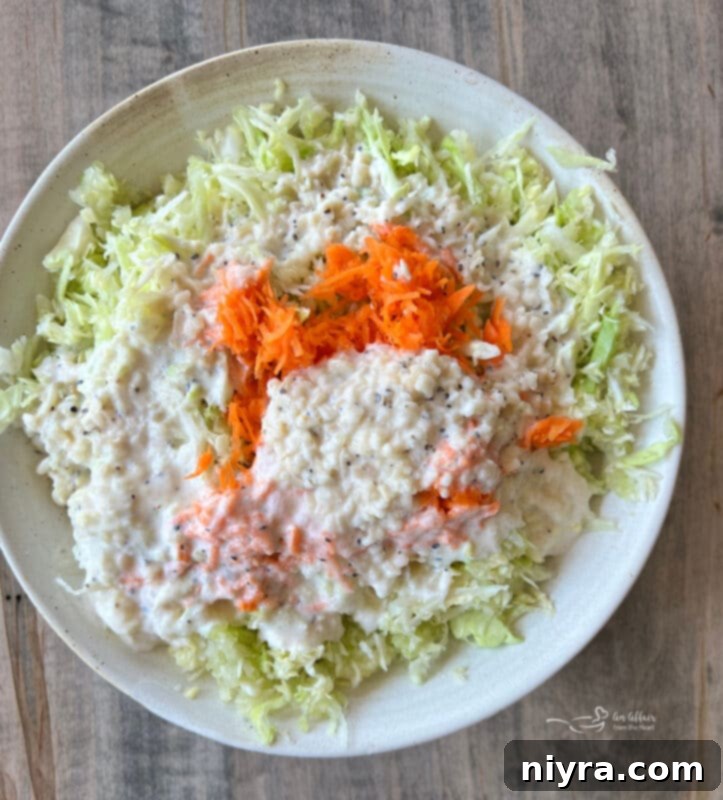 Coleslaw being tossed in a mixing bowl with a spoon