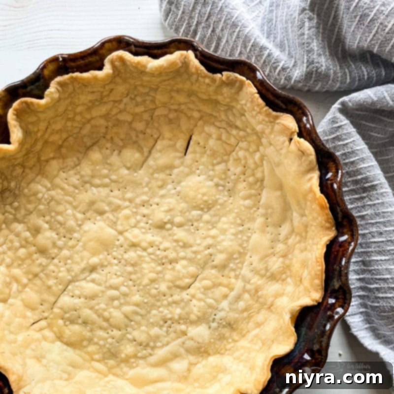 Golden-brown, flaky homemade pie crust in a metal pie dish, ready for filling.