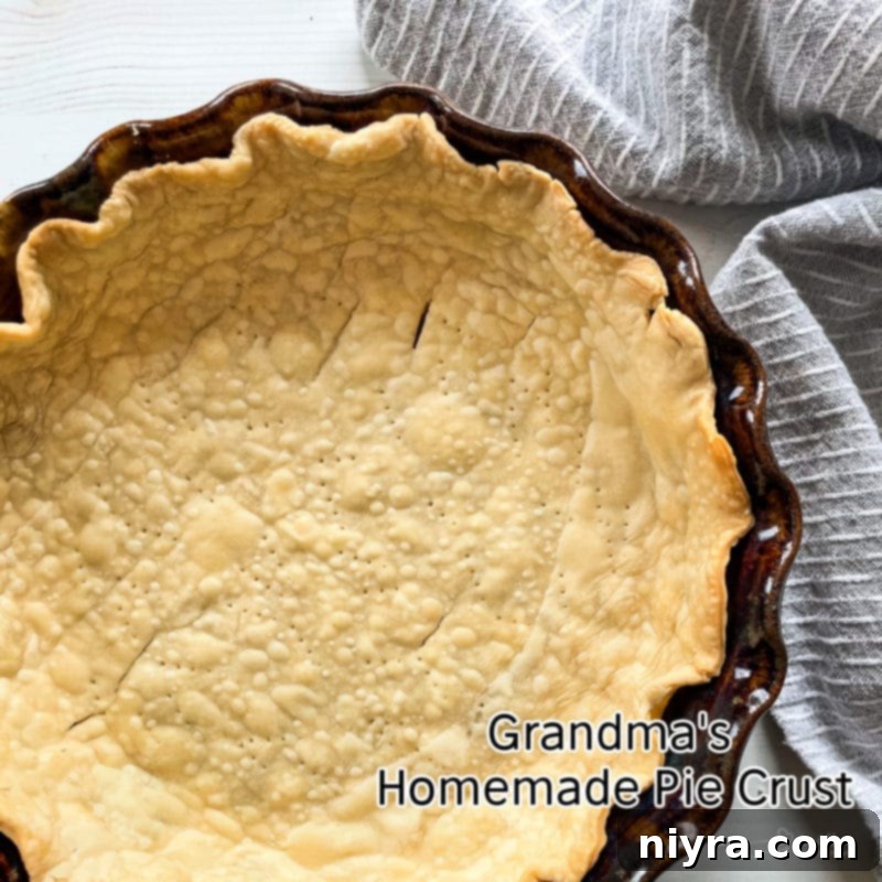 Beautifully crimped and golden-brown homemade pie crust in a metal dish, ready for filling.