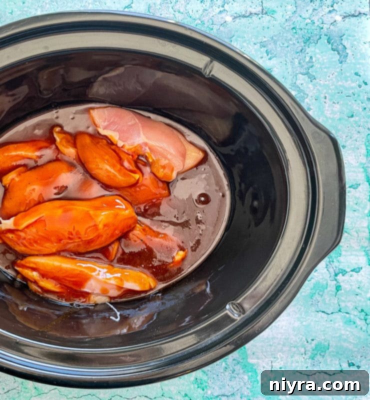 Pouring sauce over chicken in a slow cooker