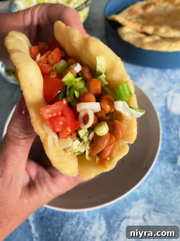 Native American Fry Bread Tacos 13 Indian Tacos in fry bread, held in hand, blue background