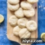 Glazed lemon cookies stacked on a wooden cutting board.