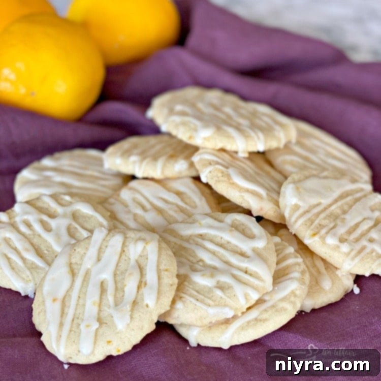 A square image featuring a pile of chewy glazed lemon cookies on a white plate