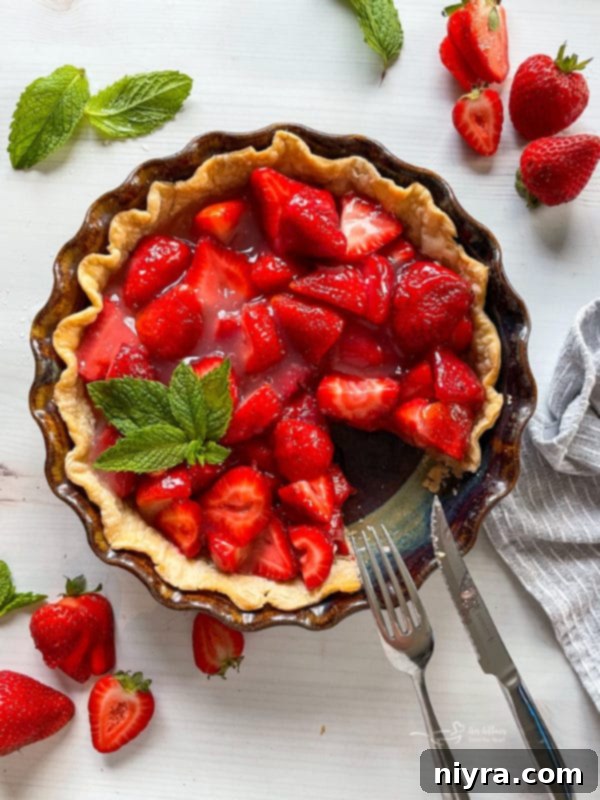 Top view of fresh strawberry pie with fork and knife