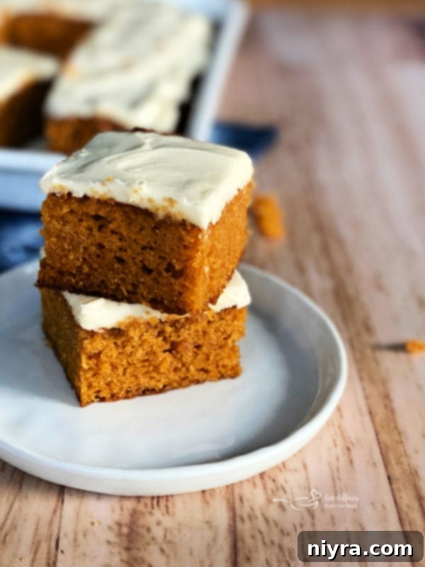 two carrot cake bars with cream cheese frosting on plate
