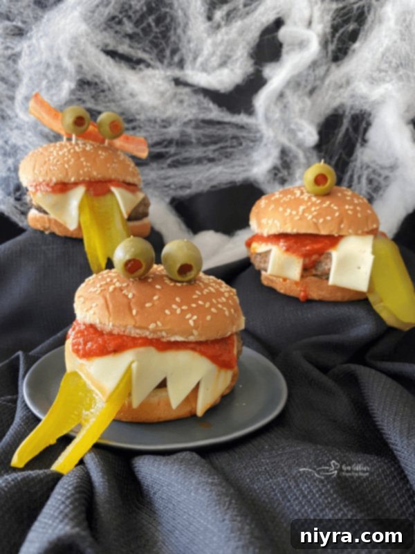 A perfectly cooked Monster Burger with Muenster cheese teeth and olive eyes, ready for a Halloween party.