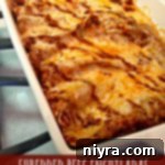 Shredded Beef Enchiladas in a baking dish with melted cheese and red sauce