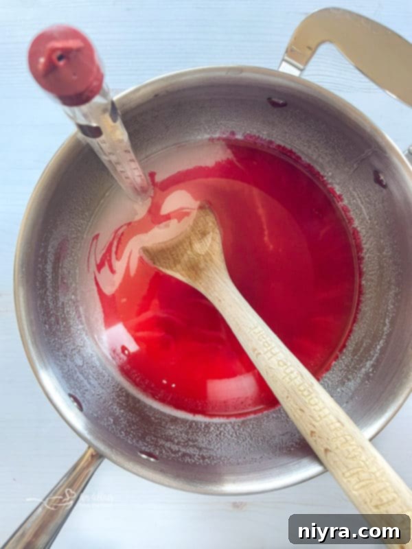 How to Make Cinnamon Rock Candy 7 Cinnamon, water, corn syrup, sugar, and food coloring in a saucepan with a candy thermometer attached