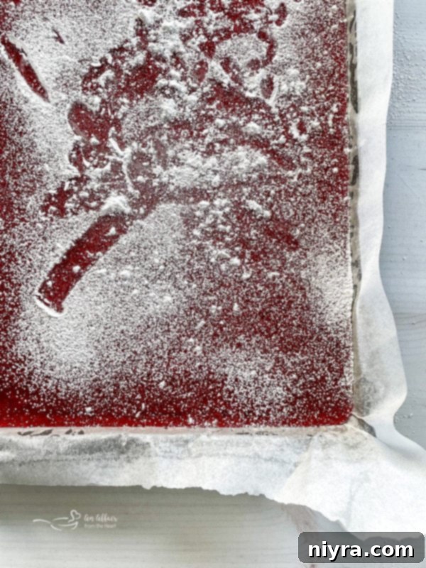 How to Make Cinnamon Rock Candy 9 Top view of cooled cinnamon rock candy in a baking sheet, being sprinkled with powdered sugar