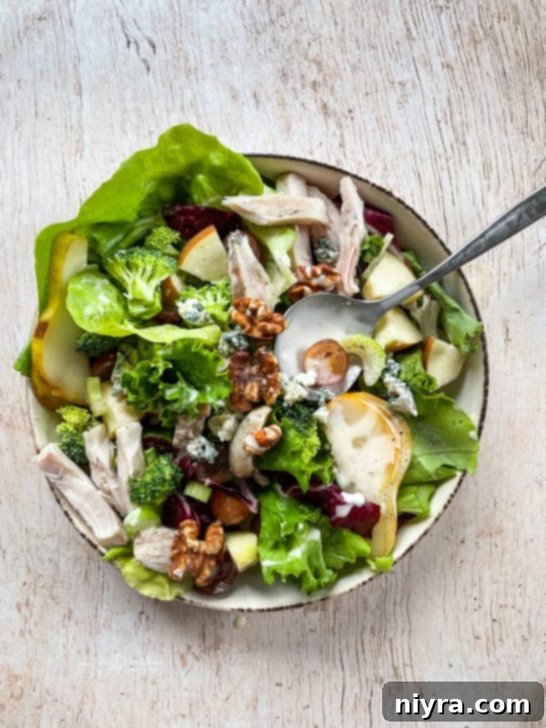 Waldorf Salad Top view of Waldorf salad with chicken in a bowl, garnished with walnuts and fruit, with a serving spoon