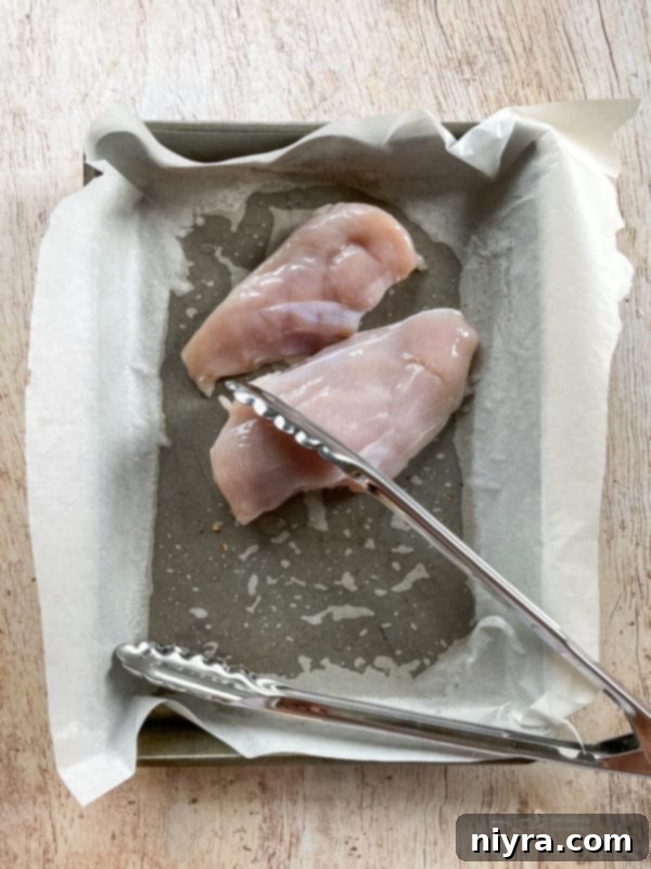 Chicken Waldorf Salad Raw chicken on a pan with tongs, ready for grilling