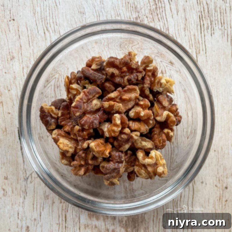 Chicken Waldorf Salad Walnuts in a glass bowl, ready for toasting