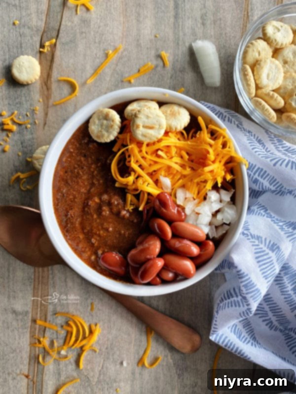 bowl of chili with beans, onion and cheese on top, showcasing the 'ways' of serving
