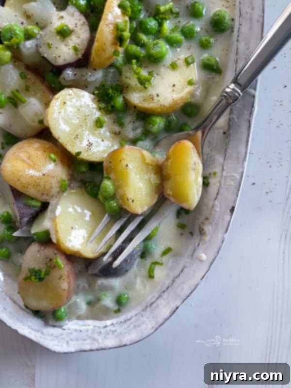 A serving of creamed new potatoes and peas with a fork, ready to be enjoyed.