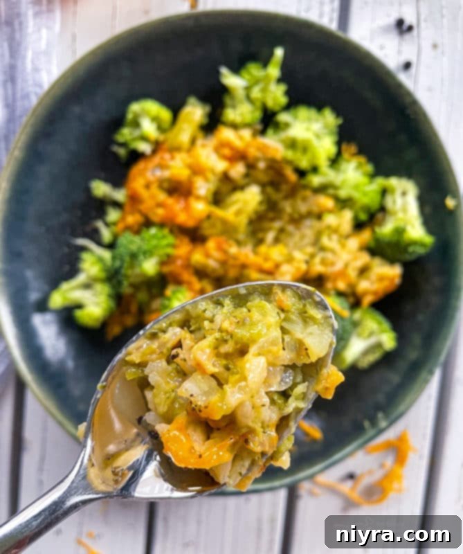 Close-up view of broccoli and cheese casserole on a spoon, showing its creamy texture.