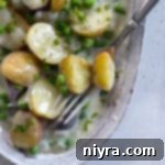 Creamed new potatoes and peas with a fork in a dish.