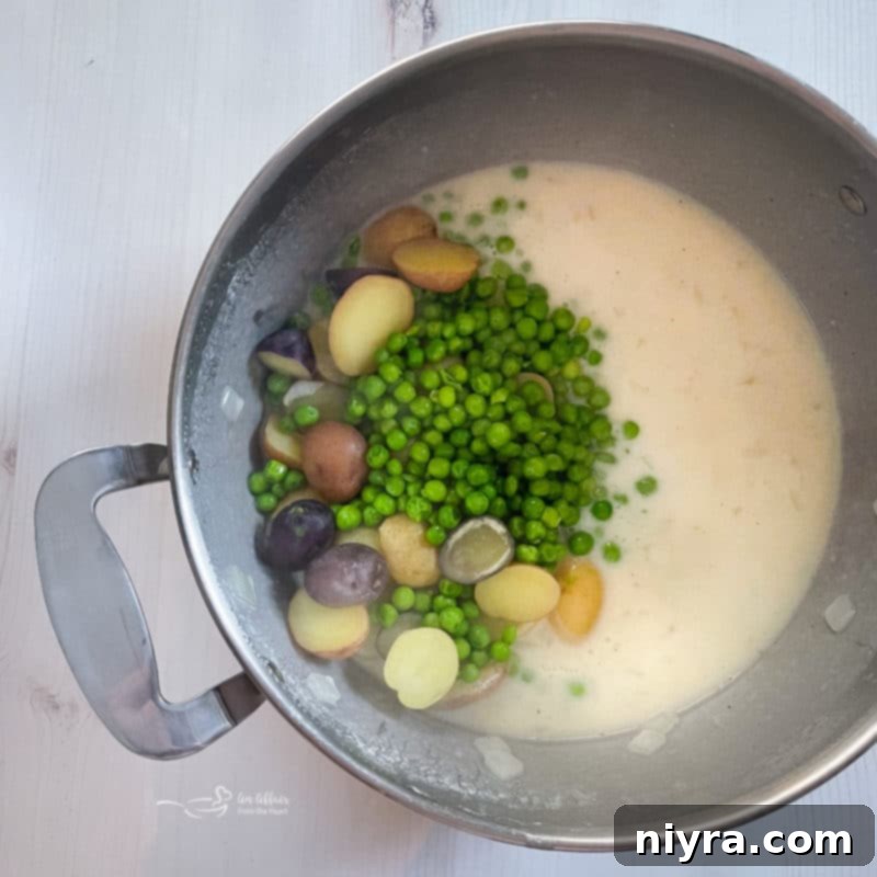 A pot filled with rich white Béchamel sauce, mixed with tender peas and potatoes.