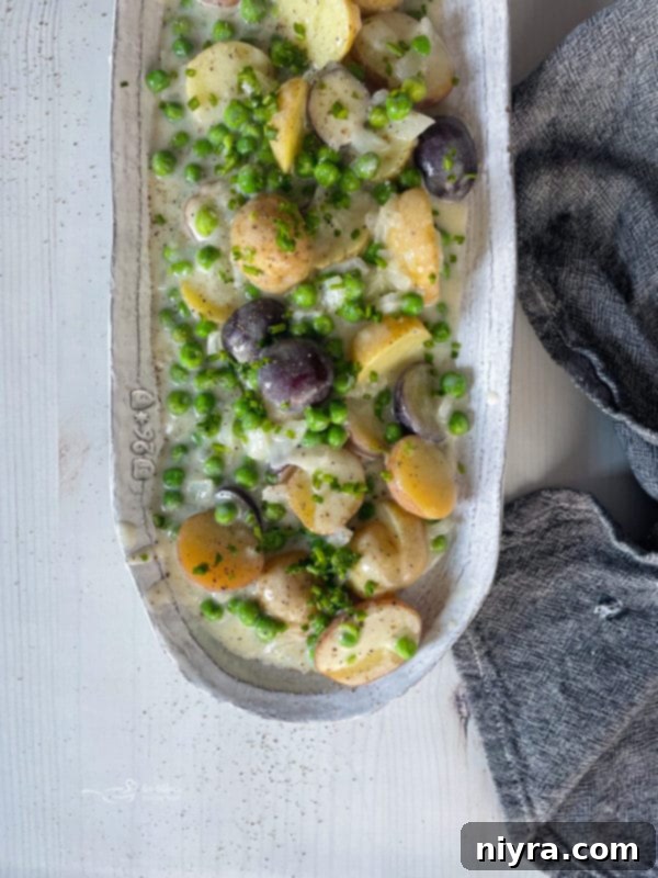 A dish brimming with creamy new potatoes and peas, garnished and ready to be served as a side dish.