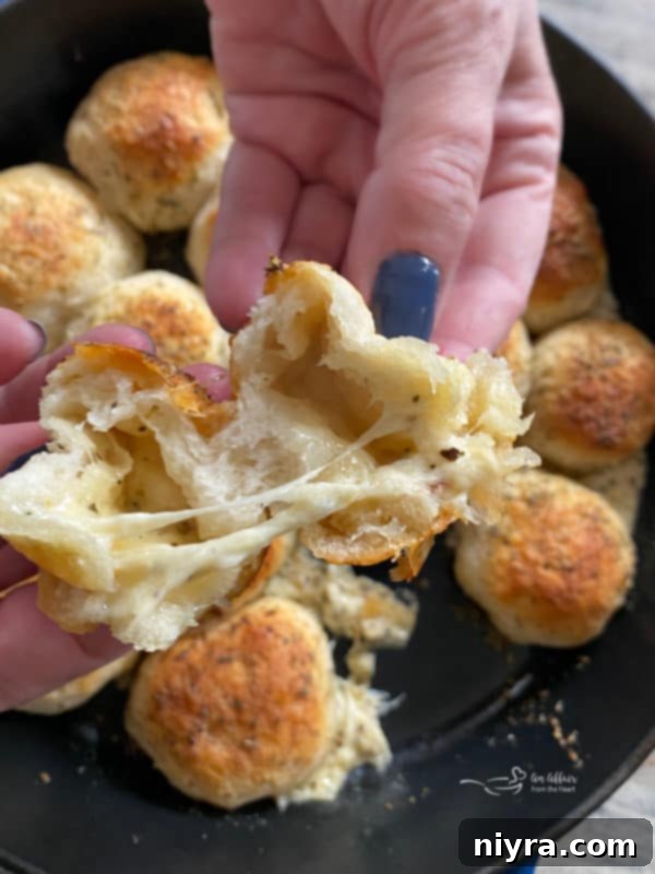 Italian Cheesy Bites 7 Hands pulling apart an Italian Cheese Bomb, revealing melted cheese inside.