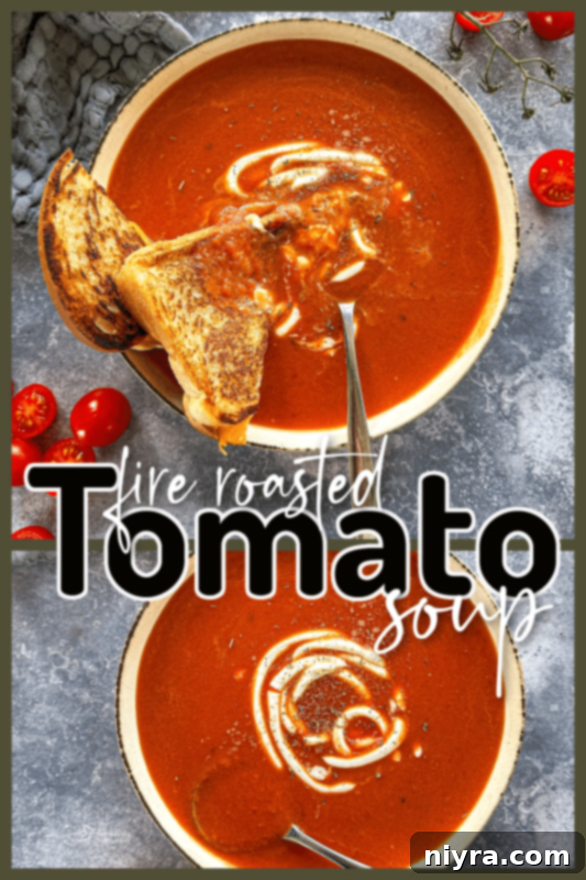 A wide shot of a bowl of fire roasted tomato soup with a spoon and grilled cheese.