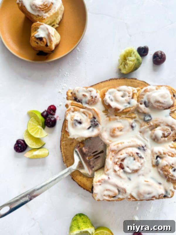 Zesty Cherry Limeade Sweet Rolls 2 Freshly baked Cherry Limeade Sweet Rolls arranged on a serving plate, showing their golden tops and sticky glaze.