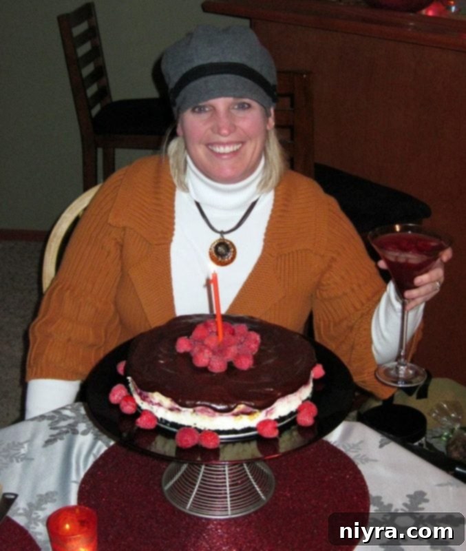 Decadent White Chocolate Raspberry Truffle Cheesecake 3 Wanda smiling with a beautifully decorated white chocolate raspberry cheesecake