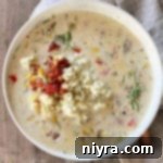 Cheesy Potato Corn Chowder with copper colored spoon and tan napkin