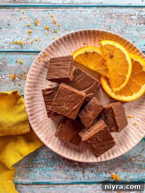 A plate featuring beautifully arranged squares of homemade Chocolate Orange Fudge, garnished with fresh orange slices, highlighting its rich texture and vibrant citrus notes.