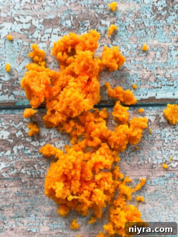 Close-up of freshly grated orange zest, emphasizing the vibrant color and fine texture that infuses the fudge with natural citrus aroma and flavor.