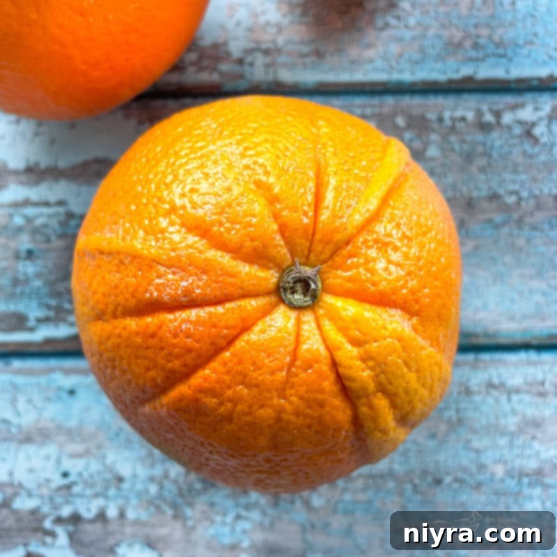 A vibrant whole orange, ready to be zested and incorporated into the rich chocolate fudge, symbolizing the fresh, natural flavor of the recipe.