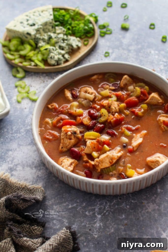 An overhead shot of a slow cooker filled with ingredients for Buffalo Chicken Chili before cooking.