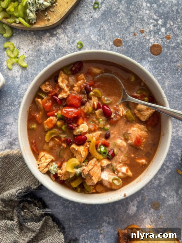 A close-up of Slow Cooker Buffalo Chicken Chili simmering in a crockpot, showing tender chicken and beans.