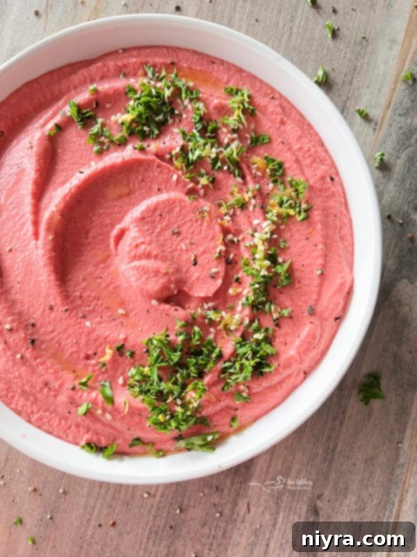 white bowl with pink hummus and parsley