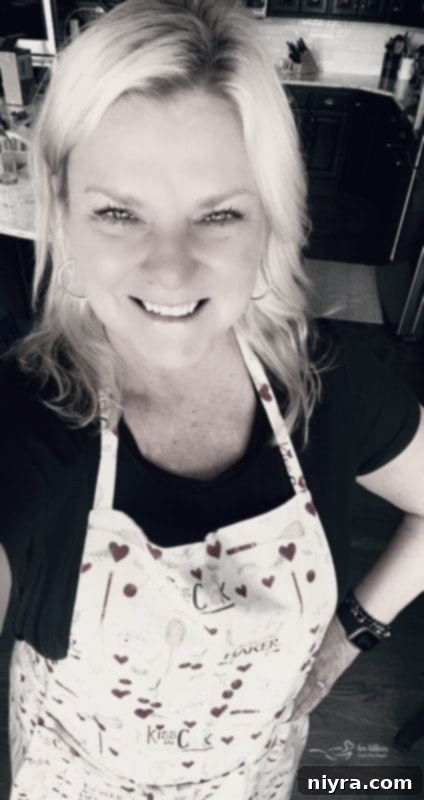 Our Ten Best Recipes from 2021 7 The author, smiling and wearing an An Affair from the Heart apron in her kitchen, ready to cook.