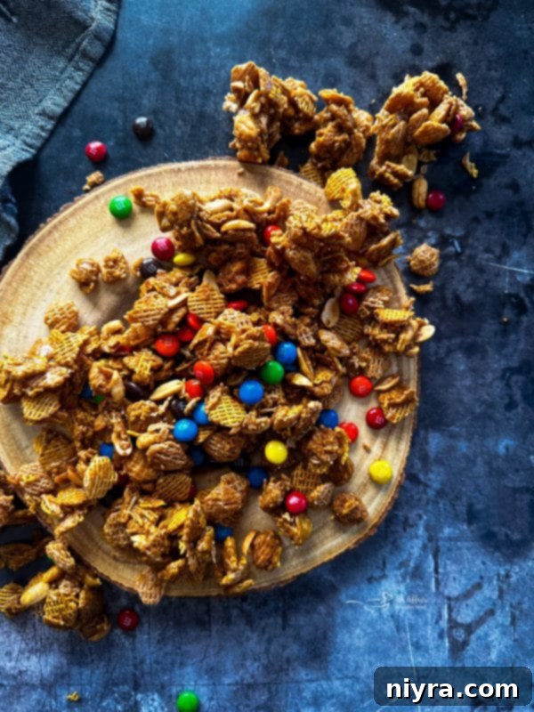 Irresistible Candy Coated Crispix Treat 17 Crispix Mix in a bowl with a hand reaching for a piece