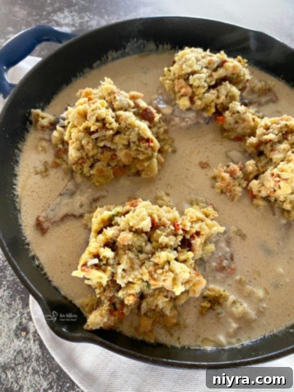 Pork Chops and Stuffing in the Oven Cooked pork chops in a skillet topped with stuffing and mushroom gravy.