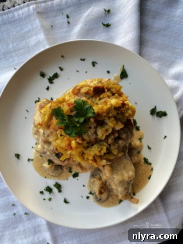 Pork Chop Stuffing Bake Casserole White plate with a baked pork chop, stuffing, and fresh herbs.