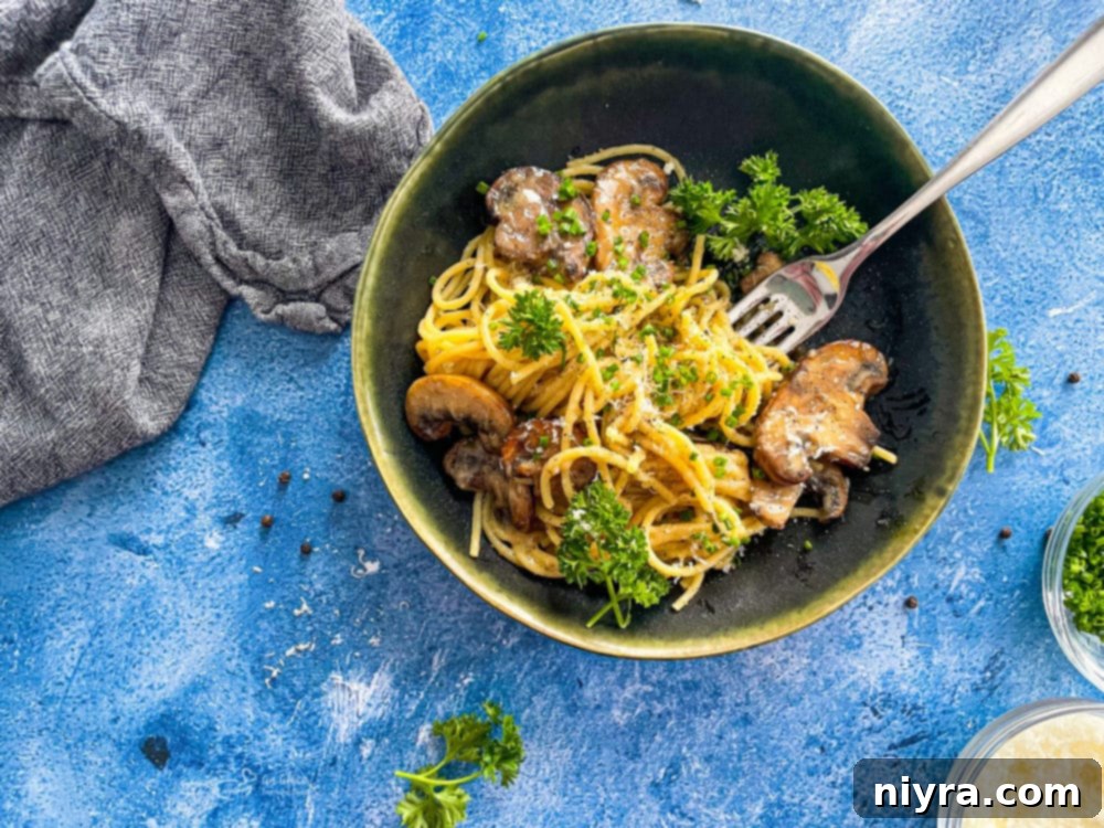 A top-down view of a single bowl of Cacio e Pepe with sautéed mushrooms, showcasing the rich, creamy texture and fresh parsley garnish.