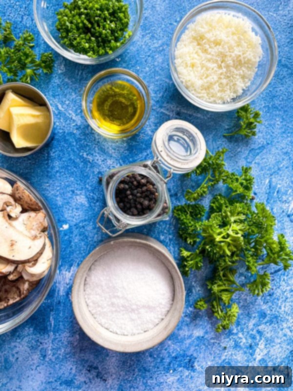 A flat lay of ingredients for Cacio e Pepe with Mushrooms: parmesan cheese, fresh parsley, chives, olive oil, salt, pepper, butter, and sliced raw mushrooms.