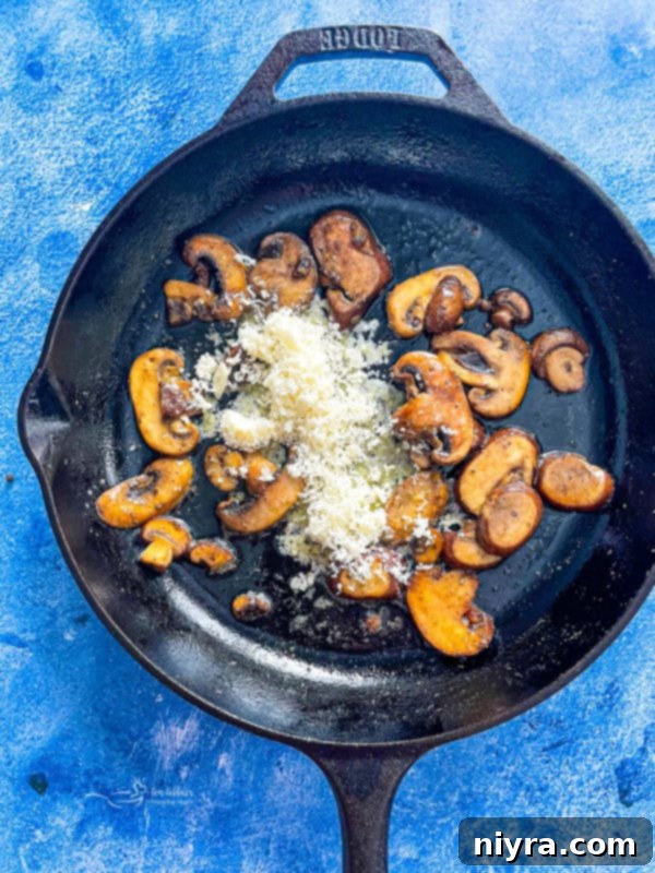 Close-up of mushrooms sautéing in a skillet, with added parmesan cheese, butter, and olive oil creating a rich base for the pasta sauce.
