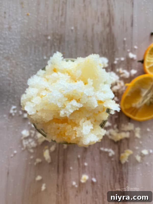 Bright lemon sugar scrub in a glass jar with fresh lemon slices.