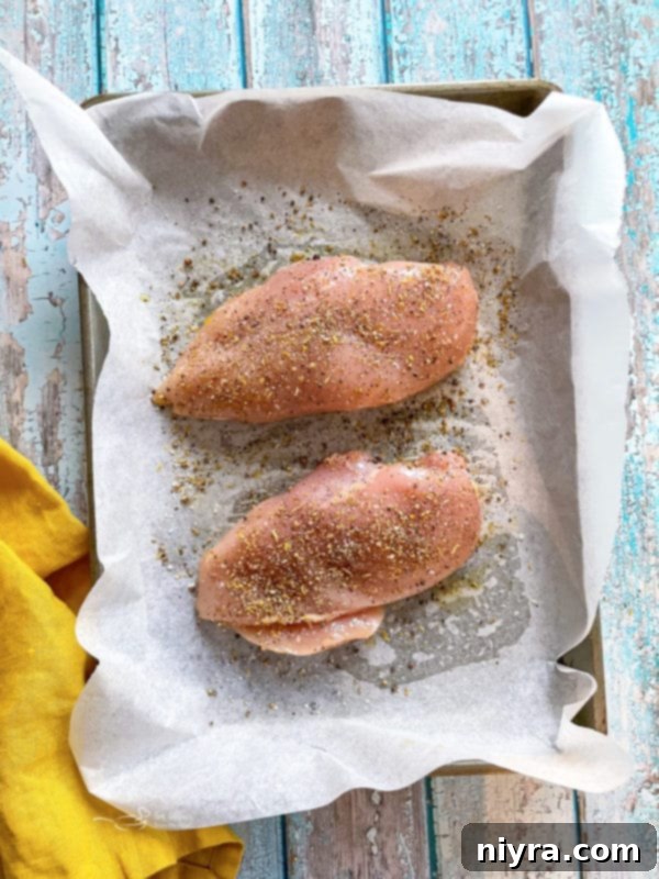 Chicken breasts seasoned generously with homemade lemon pepper mix on a baking sheet.