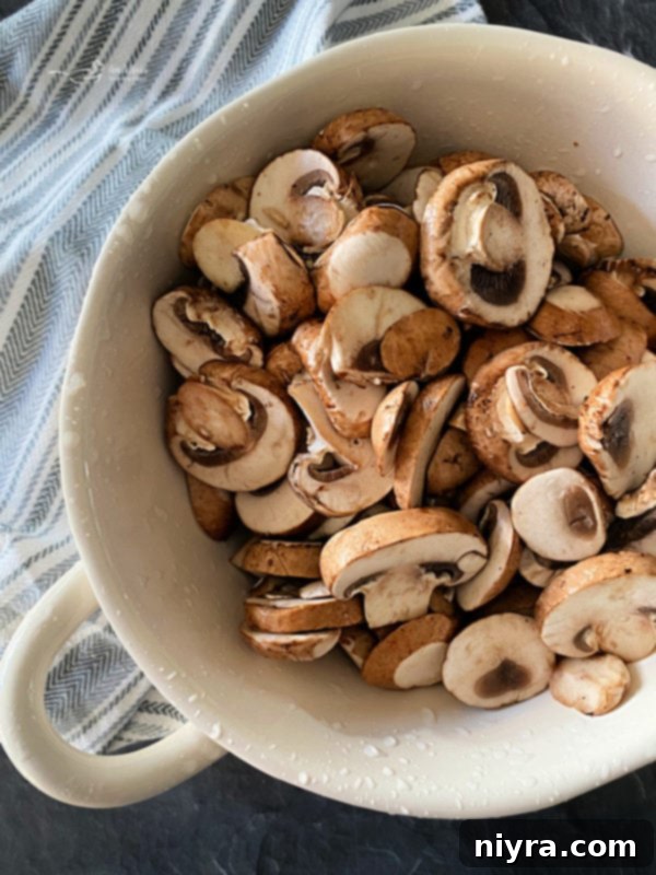 Close-up of fresh baby bella mushrooms, sliced and ready for cooking, highlighting their rich color and texture.