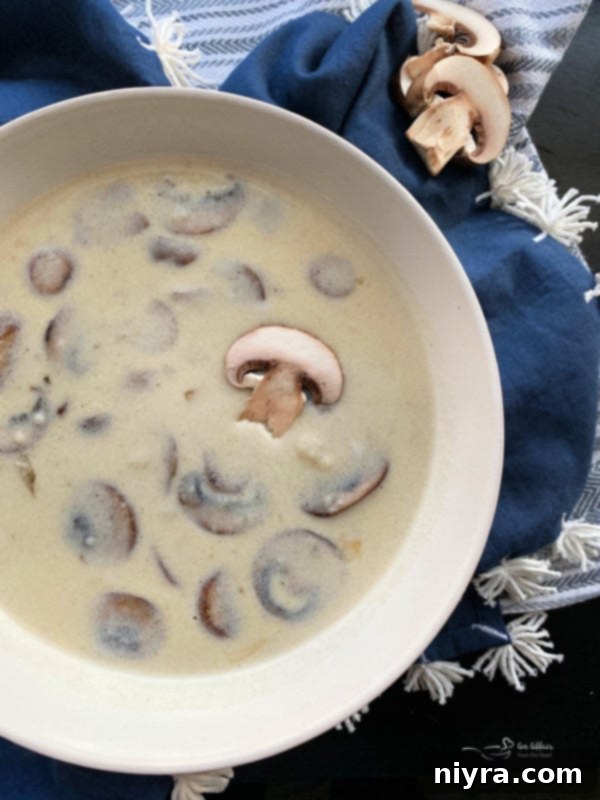 A close-up shot of a spoon scooping creamy Homemade Cream of Mushroom Soup from a bowl, garnished with parsley.