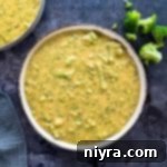 A white bowl with broccoli cheese soup in it