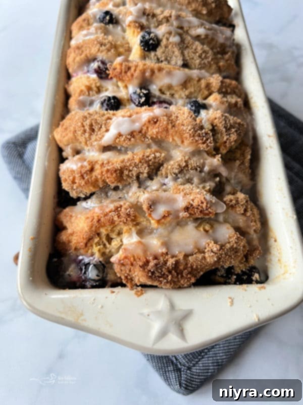 Warm Blueberry Lemon Pull-Apart Bread being drizzled with a fresh lemon glaze