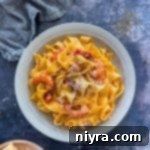 A white bowl of Crab & Shrimp Pasta with shredded cheese on top.